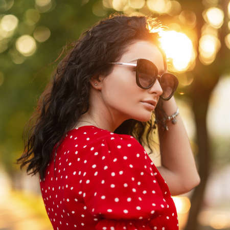 182023546-portrait-de-mode-avec-une-belle-femme-bouclée-avec-des-lunettes-de-soleil-élégantes-dans-une-robe